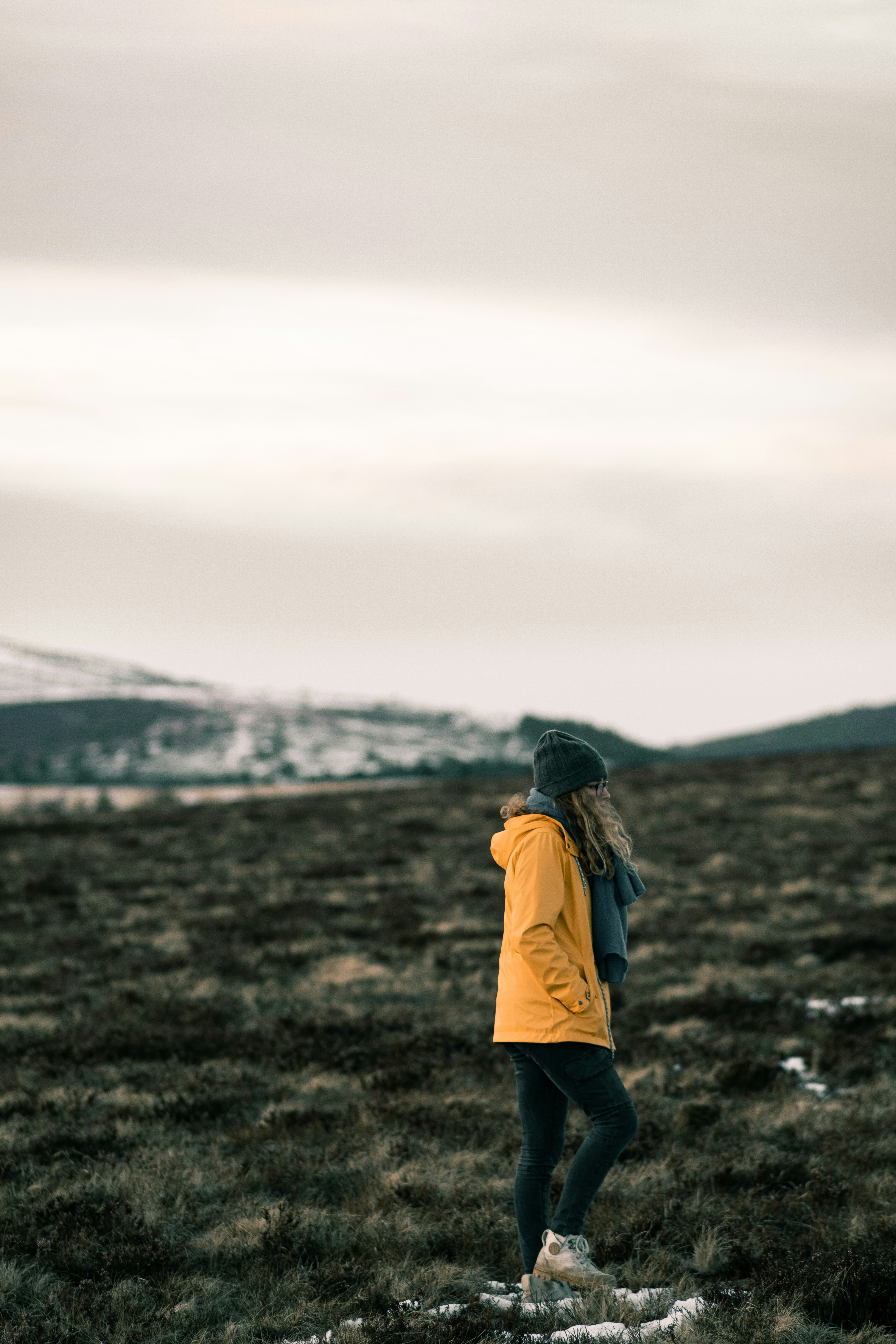 woman in yellow jacket standing on brown grass field during daytime